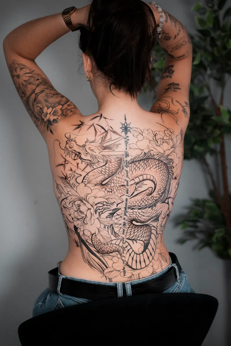 Espalda completa tatuada con un dragón oriental de línea fina entre peonías, bambú y nubes