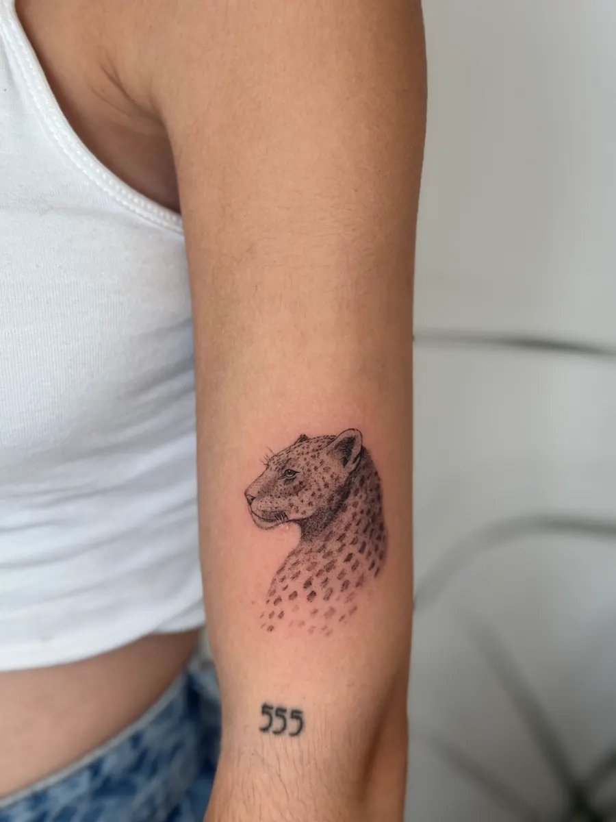 Cabeza de leopardo tatuada con puntillismo y sombreado fino en el brazo